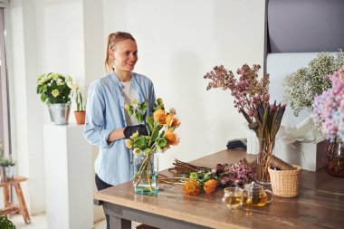 Çiçekçide çalışan gülümseyen bir çiçekçi.