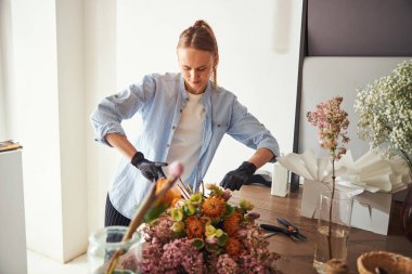 Çiçek tasarımcısı harika bir buketi sicimle sarıyor.