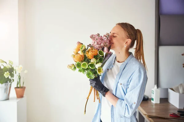 Floristin genießt den Duft von Blumen in ihren Händen — Stockfoto