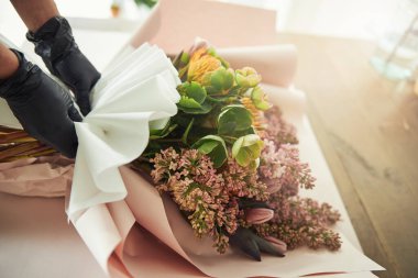 Deneyimli çiçekçi muhteşem bir çiçek düzenini paketliyor.