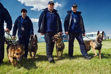 Havaalanında yürüyen köpekli neşeli güvenlik görevlileri.