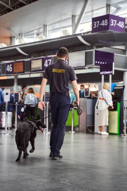 Havaalanı terminalinde yürüyen köpeği tespit eden bir güvenlik görevlisi.