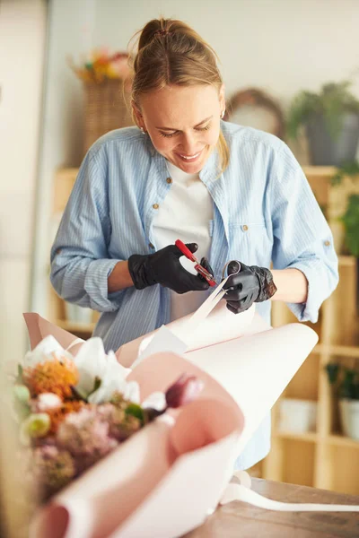 Joyous флориста в нітрилових рукавичках, що закінчують квіткову композицію — стокове фото
