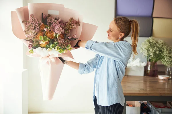 Професійний флорист, який захоплюється завершеною квітковою композицією — стокове фото