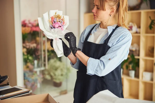 Florista con experiencia enfocada examinando un arreglo floral en sus manos — Foto de Stock