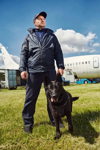 Security officer with detection dog standing outdoors at aerodrome