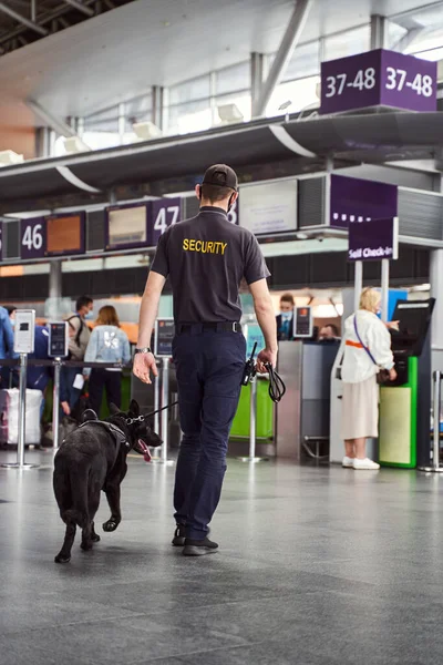 Security worker with detection dog walking down airport terminal