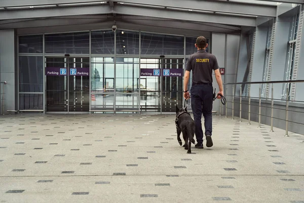 Oficial de segurança com cão da polícia a caminho do edifício de estacionamento — Fotografia de Stock