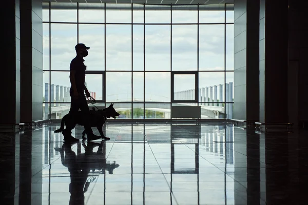 Trabalhador da segurança e cão da polícia caminhando pelo terminal do aeroporto — Fotografia de Stock