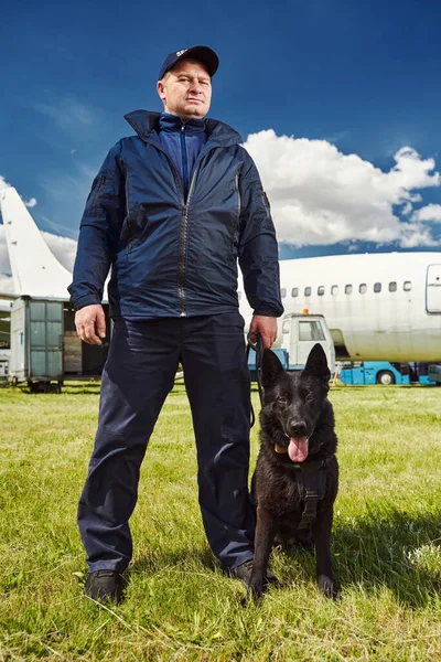 Male security officer with dog standing outdoors at aerodrome Royalty Free Stock Photos