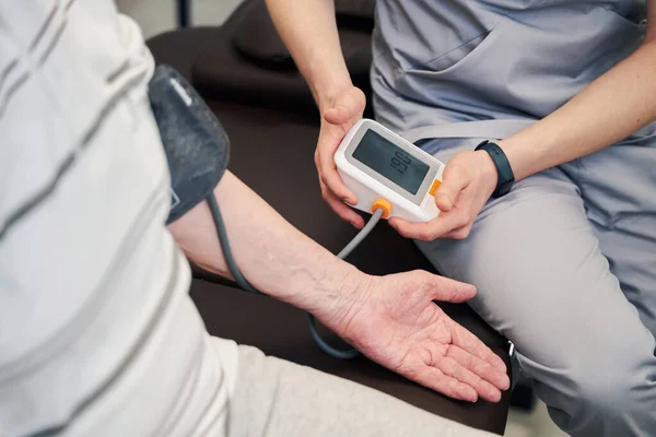 Läkare som använder blodtrycksmätare på pensionär — Stockfoto