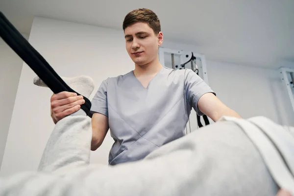 Medical person attaching ankle strap to patient leg