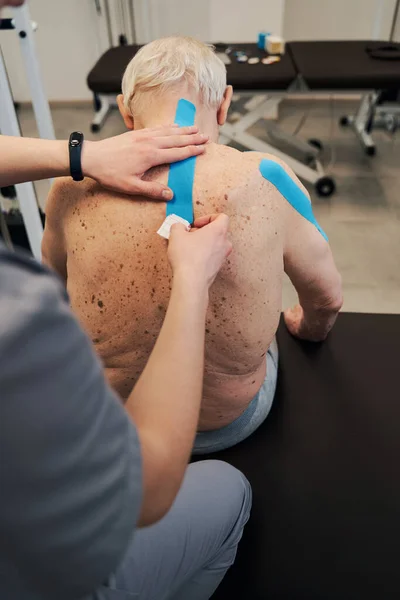 Orthopäde legt Therapieband auf den Rücken — Stockfoto