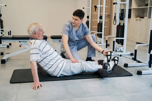 Emekli, ortopedist talimat verirken bacaklarını piste koyuyor. — Stok fotoğraf