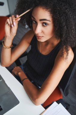 Alnına kalemle dokunmakla meşgul bir kadın.