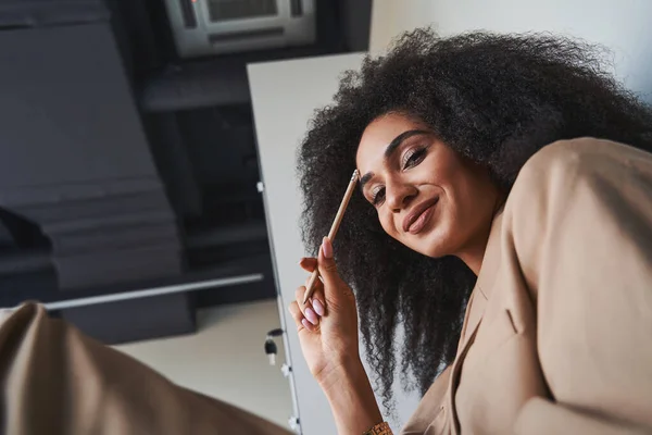 Gladsome senhora com bela maquiagem sentada sozinha e sorrindo — Fotografia de Stock