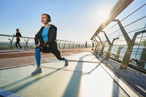 Ung smal kvinna gör träning på urban bro — Stockfoto