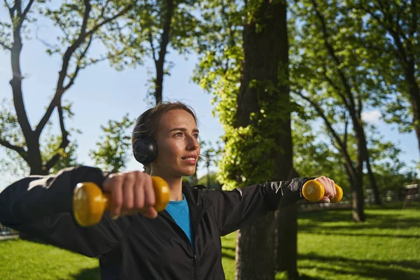 Mulher feliz exercitando braços com equipamentos ao ar livre — Fotografia de Stock