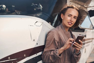 Havaalanında cep telefonu kullanan çekici bir genç kadın.