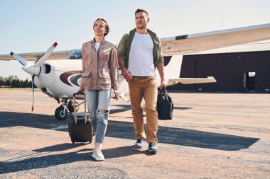 Seyahat çantalı güzel bir çift havaalanında yürüyor.