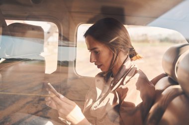 Uçakta akıllı telefon kullanan çekici bir genç kadın.