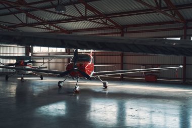Havaalanı hangarında iki küçük kırmızı ve beyaz uçak.