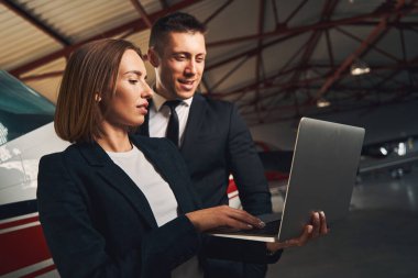 İş arkadaşları uçak hangarında defter kullanıyorlar.