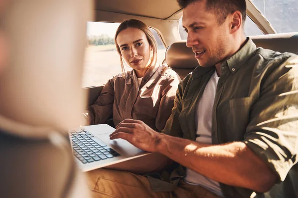 Beautiful young couple using laptop in car — Stock Photo, Image