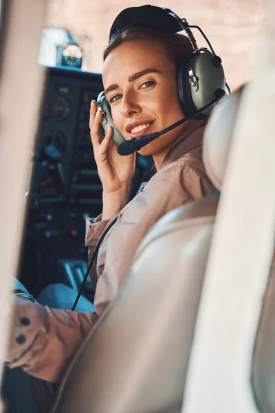 Jovencita alegre sentada en cabina de piloto de avión — Foto de Stock