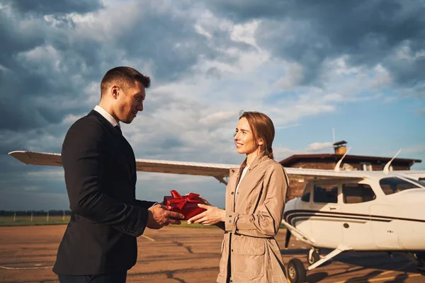 Liefdevolle man geeft cadeau aan zijn vriendin op het vliegveld — Stockfoto