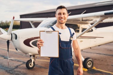 Havalimanında duran dosyasıyla neşeli erkek işçi.