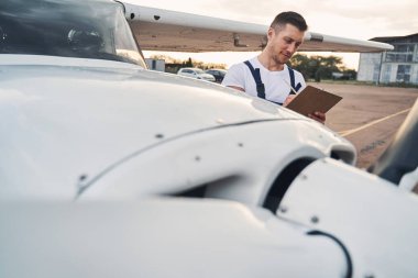 Havalimanında panoya yazı yazan yakışıklı bir erkek işçi.