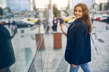 Güzel bir kadın gülüyor ve el sallıyor.