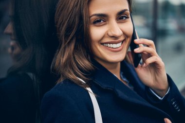 Çekici bir kadın, güzel bir ruh hali içinde, cep telefonuyla.