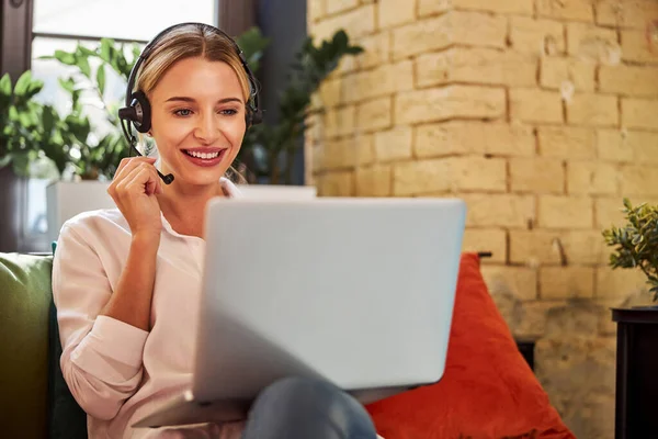 Charming business lady in headphones talking with business partner on laptop — Stock Photo, Image