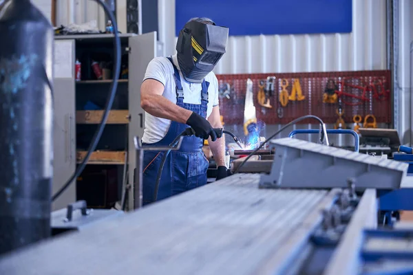 Man monteur in lassen masker werken in de garage — Stockfoto