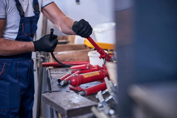ガレージでポータブル油圧自動車修理ツールを組み立てる男性労働者 — ストック写真