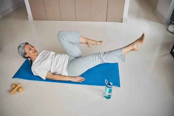 Formda bir kadın karın kası egzersizi yapıyor. Evde bacaklarını esnetiyor. — Stok fotoğraf