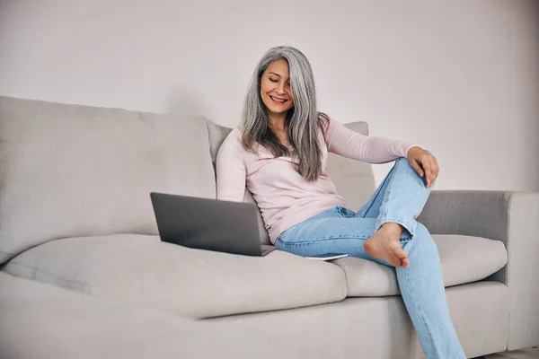 Όμορφη γυναίκα freelancer κοιτάζοντας στην οθόνη του υπολογιστή της, ενώ σερφάρετε στο διαδίκτυο στο σπίτι — Φωτογραφία Αρχείου