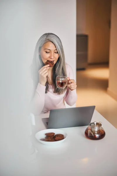 Femme charmante utilisant un carnet et prenant le petit déjeuner à la maison — Photo