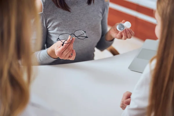 Woman seller demonstrating modern lens and eye glass in optician clinic — Stock Photo, Image