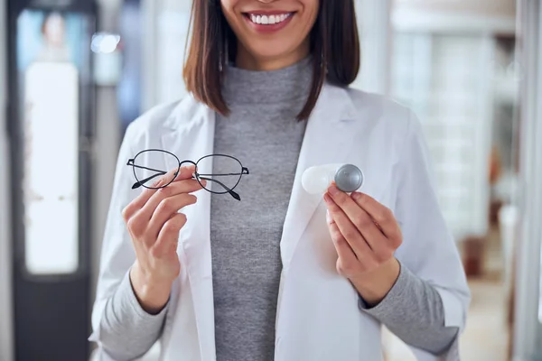 Médico alegre feliz oftalmologista demonstrando diferentes ferramentas para os olhos de cuidado — Fotografia de Stock