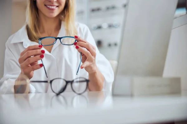Beyaz bluzlu zarif bir kadın göz hekimliği kliniğinde gözlük için yeni lensler seçiyor. — Stok fotoğraf