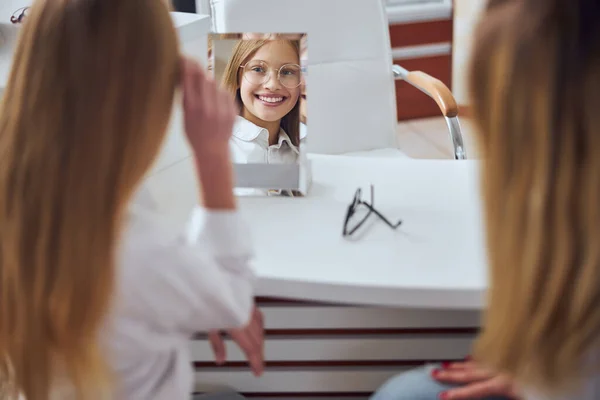 Щаслива усміхнена школярка в стильних окулярах в оптичному магазині — стокове фото