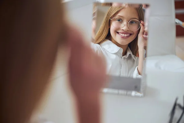 Beautiful positive school lady looking at the reflection in room indoors — Stock Photo, Image