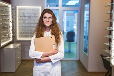 Göz alıcı kadın göz doktoru optik mağazada duruyor.