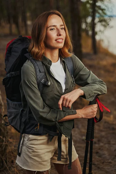 Beautiful lady leaning on walking poles in forest