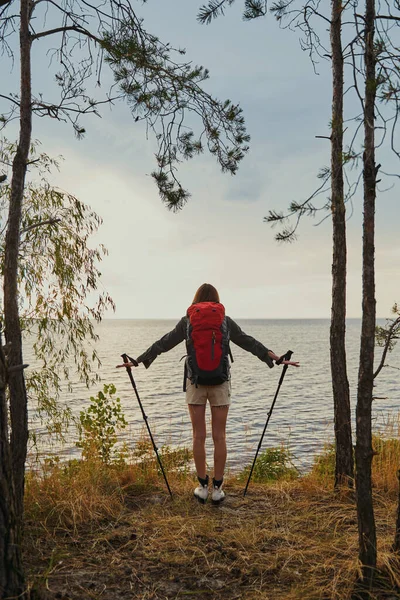 Vrouw op de oever van de rivier met wandelpalen — Stockfoto