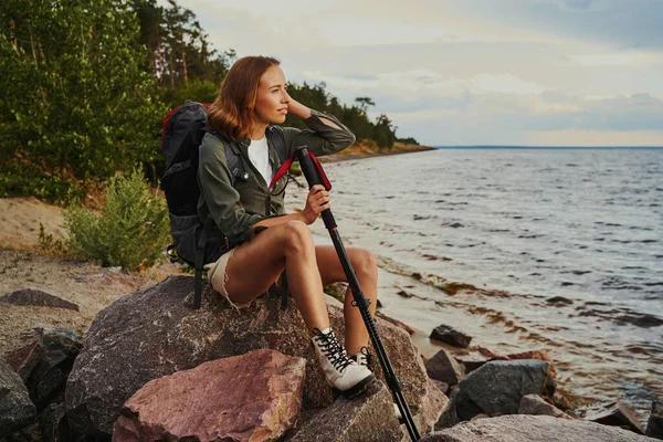 Escursionista facendo una sosta e riposando sulla roccia vicino al lago — Foto Stock