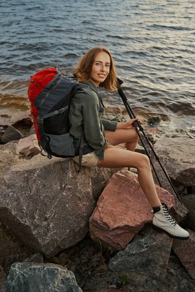 Donna dai capelli rossi seduta sulla roccia e sorridente alla macchina fotografica — Foto Stock